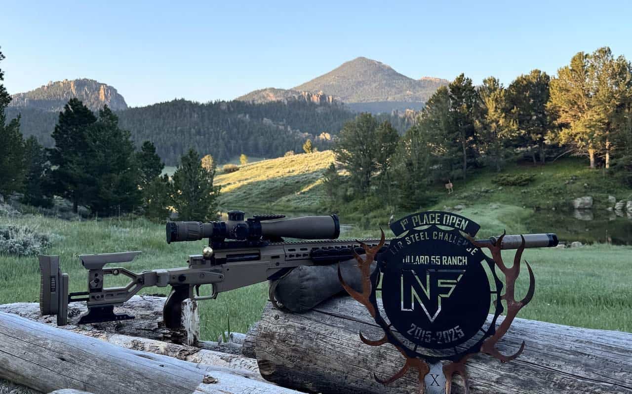 Competition rifle on a log at a mountain range beside a first-place NRL Steel Challenge trophy